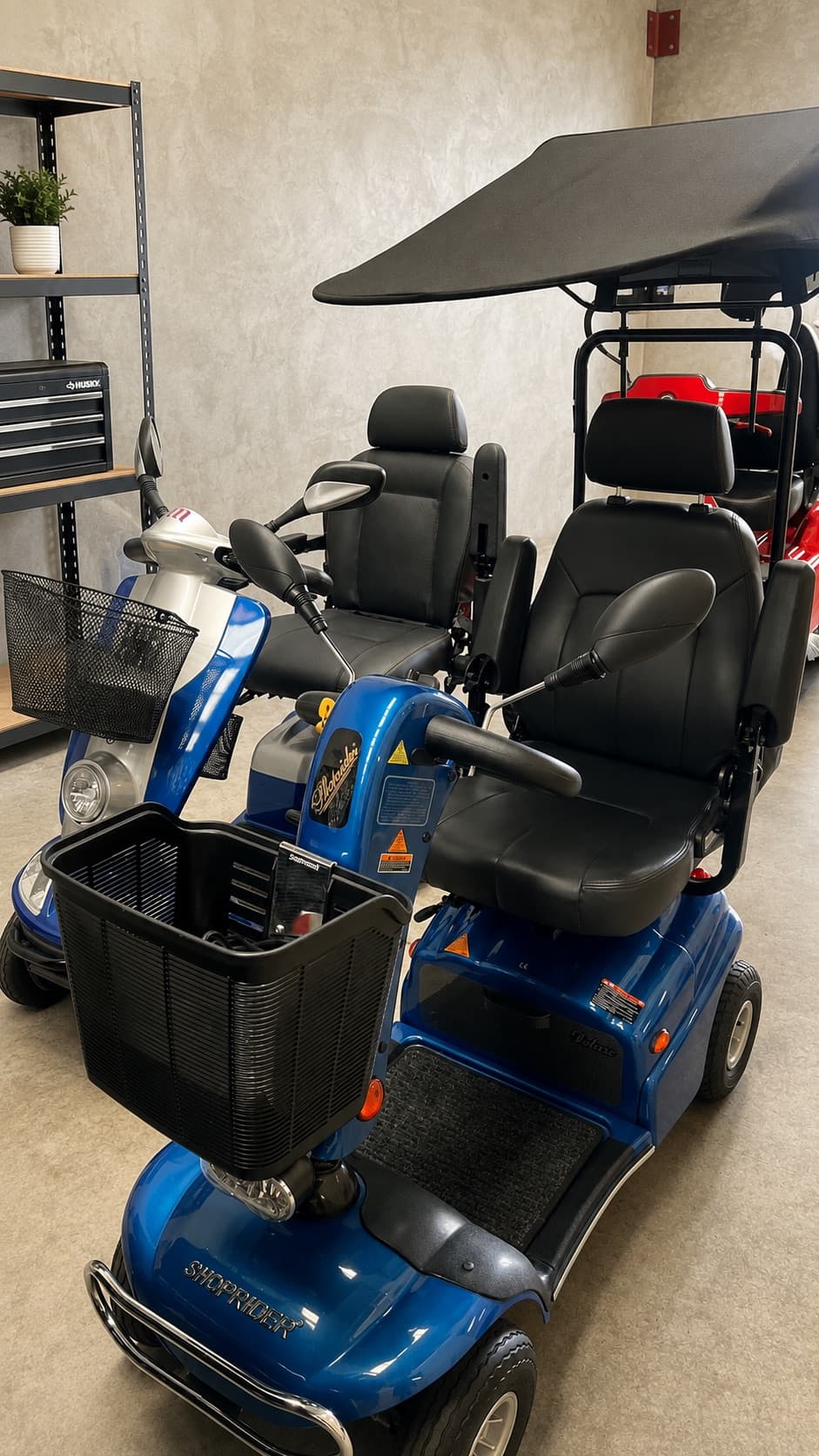 Blue four-wheel mobility scooters with a fitted canopy at Battery Factory Direct in Maddington